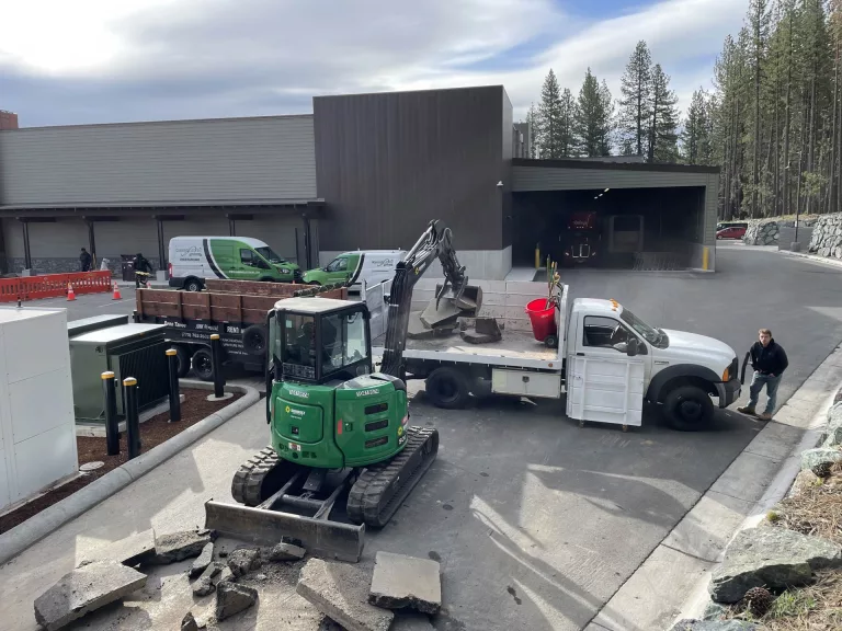 A track loader loading a Reno Tahoe Junk Removal truck with broken pieces of cement